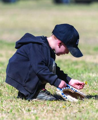 We have all been there and yes outfield is just boring. This unidentified young boy is checking out the “flowers” while he patiently awaits a ball to come his way. Ron Francis Photo