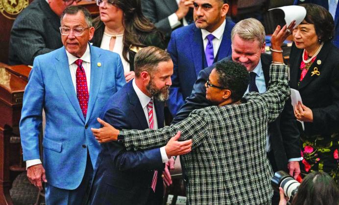 ACROSS THE AISLE State Rep. Toni Rose (D-Dallas) hugs fellow Reps. Dustin Burrows (R-Lubbock) and David Cook (R-Mansfield) after Burrows won the vote for speaker Jan. 14. | ELI HARTMAN/THE TEXAS TRIBUNE
