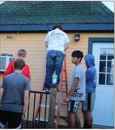 Students from the PHS JV Football team hang lights in the park for the holiday extravaganza. Staff Photo