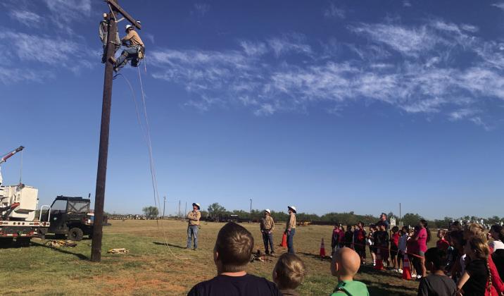 SURVIVAL PRACTICE Over 300 students from surrounding schools participated in South Plains Electric Company (SPEC) field trip. Students learned the importance of safety when working with electricity. New recruit Woodrow climbed the pole to save the dummy, Bob. The young onlookers watch with anticipation at what will happen next. | ANNA GIBSON PHOTO