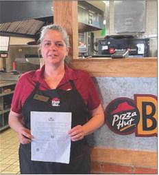 Liz Ruth holds the message from the Sr. Manager, Operations with a congratulations for being in the top 100 Pizza Huts in the nation.