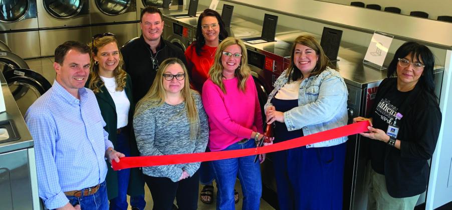 NEW LAUNDROMAT Amy Rektenwald and Hayley Mason cut the red ribbon during their grand opening on Jan. 16. Beside them on the left are Owners Jordan and Leigh Madewell, Tye Mason, Misti Day, Lupe Lazcano, and Christina Jones. | ANNA GIBSON PHOTO