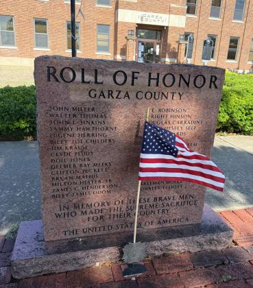 LASTING LEGACY A small American flag stands before the Garza County Roll of Honor monument on the courthouse square in Post, serving as a tribute to local servicemen who made the ultimate sacrifice in defense of the United States. | STEPHANIE ALLEN