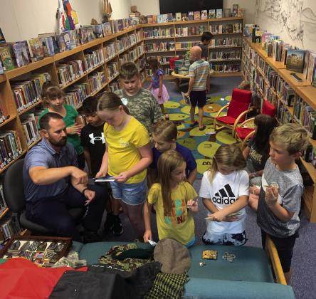 SPECIAL GUEST Dr. Kyle Gunn and Captain (U.S. Army) shares photos and artifacts from his trips to Afghanistan after reading aloud to the Public Library Reading Program participants, Wednesday. | ANNA GIBSON