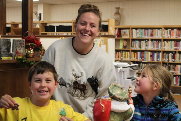 HOME SCHOOL KIDS ENJOY OPEN HOUSE Home School mom Rayanne Dennison, is with Tristian and Anna Rae as they sample the goodies at the Library’s Open House last Thurs. The Dennison are regular library patrons and enjoy special events. Tristan and Anna Rae are quick to tell you their favorite author is John Erickson. | JULIA CHILDS PHOTO