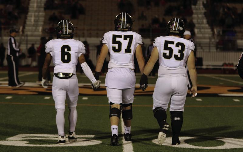 UNIFIED TEAM Ian Vergara, Cooper Osborn, and Mason Wright step to the center of the field for the coin toss before their big win that will take them to the Regional Semifinals against the Sunray Bobcats on Friday, November 29. | KHLOE SMITH PHOTO