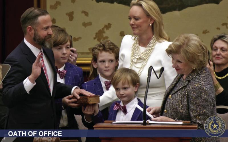 ELECTED TX SPEAKER State Rep. Dustin Burrows was administered the oath of office as Speaker of the Texas House by Secretary of State Jane Nelson (right) during opening day ceremonies on the House floor on Tuesday, Jan. 14, 2025, as Burrows’ wife, Elisabeth (in white dress), and children look on. | BOB DAEMMRICH FOR THE TEXAS TRIBUNE