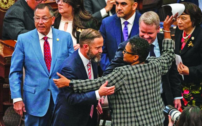 ACROSS THE AISLE State Rep. Toni Rose (D-Dallas) hugs fellow Reps. Dustin Burrows (R-Lubbock) and David Cook (R-Mansfield) after Burrows won the vote for speaker Jan. 14. | ELI HARTMAN/THE TEXAS TRIBUNE