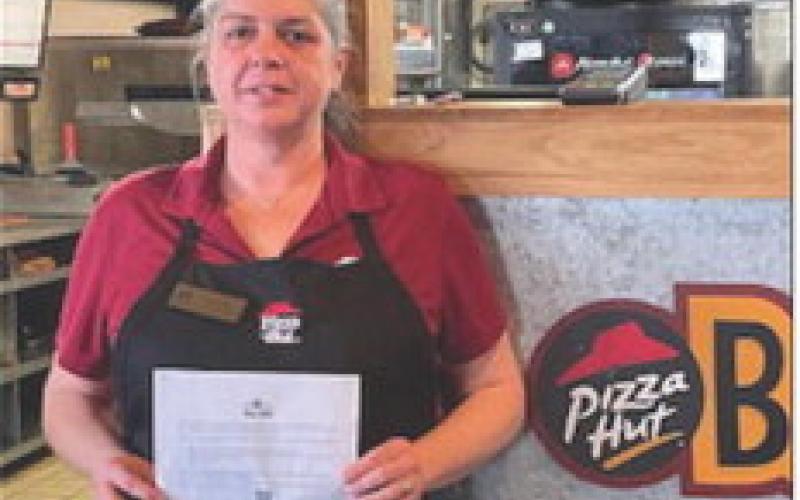 Liz Ruth holds the message from the Sr. Manager, Operations with a congratulations for being in the top 100 Pizza Huts in the nation.