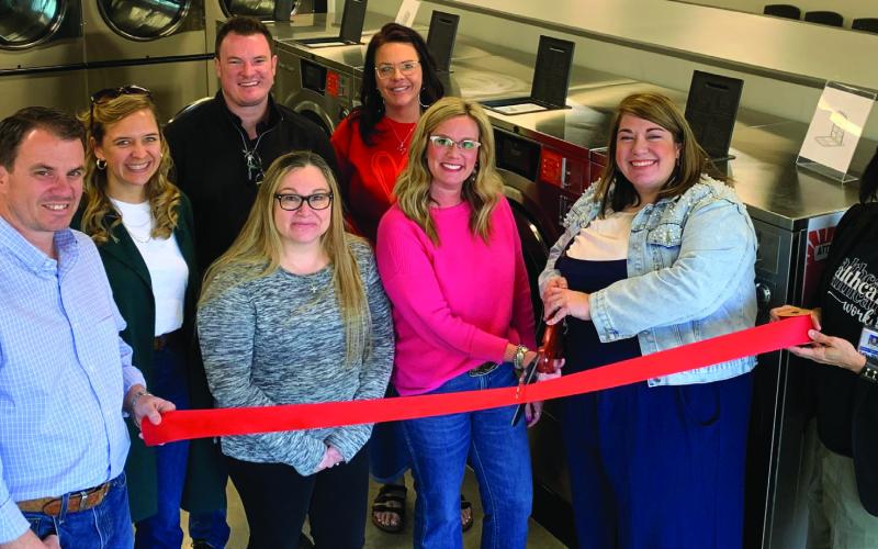 NEW LAUNDROMAT Amy Rektenwald and Hayley Mason cut the red ribbon during their grand opening on Jan. 16. Beside them on the left are Owners Jordan and Leigh Madewell, Tye Mason, Misti Day, Lupe Lazcano, and Christina Jones. | ANNA GIBSON PHOTO