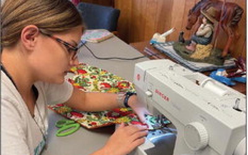Trinity Ochoa is shown sewing up one of the bibs for the 4-H Community Service Project. Trinity a home school student is a senior Garza County 4-H group member. Photo by Julia Childs