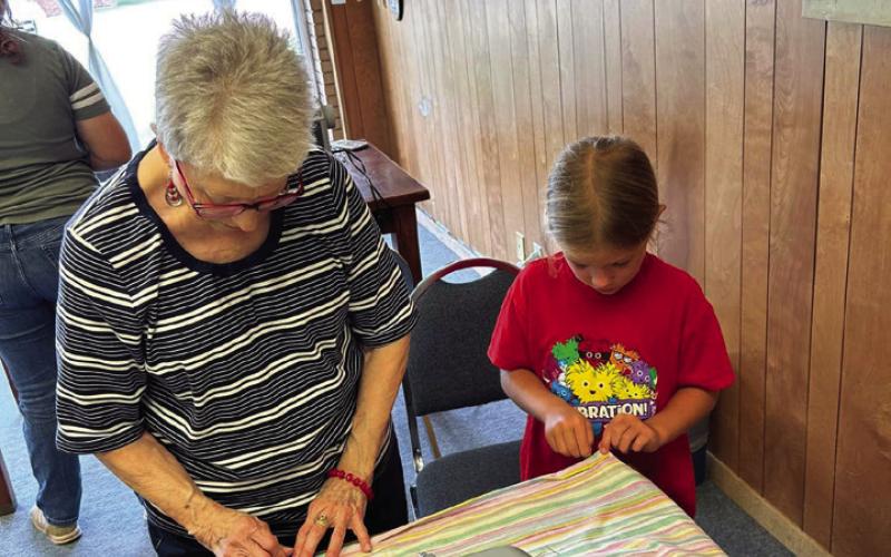 HEMMING Debbie Sneed assists Zoee Ray with the hem of her apron during the 4-H sewing class last Wednesday. | XANE REITER PHOTO