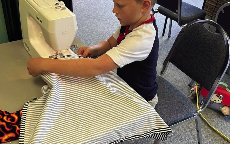METICULOUS Connor Griffin focuses on sewing the hem of his apron during the 4-H sewing class at the Garza County Extension Office. | XANE REITER PHOTO