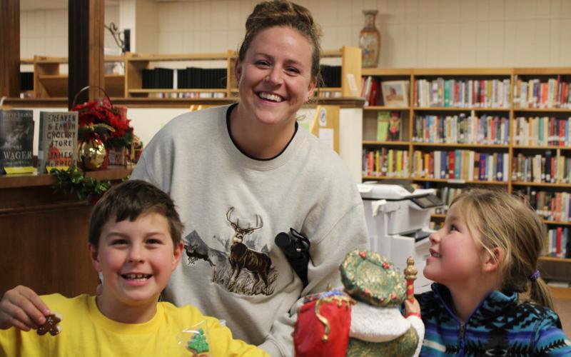 HOME SCHOOL KIDS ENJOY OPEN HOUSE Home School mom Rayanne Dennison, is with Tristian and Anna Rae as they sample the goodies at the Library’s Open House last Thurs. The Dennison are regular library patrons and enjoy special events. Tristan and Anna Rae are quick to tell you their favorite author is John Erickson. | JULIA CHILDS PHOTO