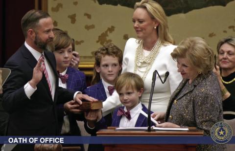 ELECTED TX SPEAKER State Rep. Dustin Burrows was administered the oath of office as Speaker of the Texas House by Secretary of State Jane Nelson (right) during opening day ceremonies on the House floor on Tuesday, Jan. 14, 2025, as Burrows’ wife, Elisabeth (in white dress), and children look on. | BOB DAEMMRICH FOR THE TEXAS TRIBUNE