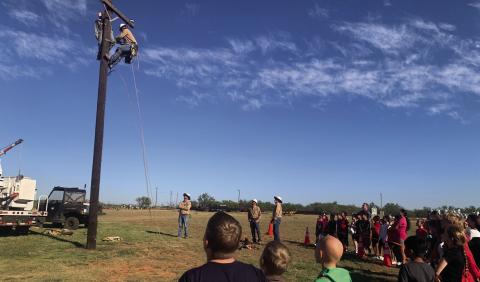 SURVIVAL PRACTICE Over 300 students from surrounding schools participated in South Plains Electric Company (SPEC) field trip. Students learned the importance of safety when working with electricity. New recruit Woodrow climbed the pole to save the dummy, Bob. The young onlookers watch with anticipation at what will happen next. | ANNA GIBSON PHOTO