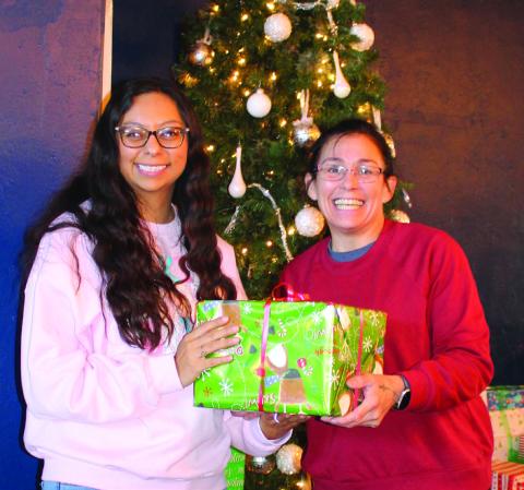Dora Bishop, Headstart Family Services Coordinator, accepts the Winehouse 127 Angel Tree gifts from Michele Liston. Over 150 gifts will make their way to 41 children this Christmas season. Photo by Julia Childs