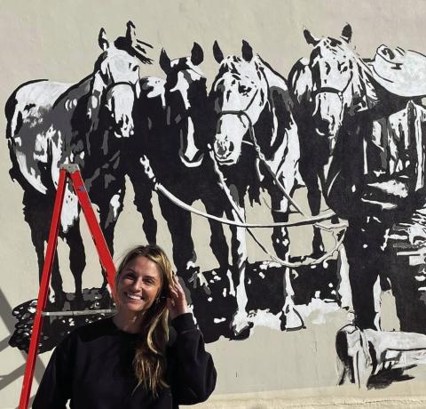 MOREMURALS Street Artist Calina Mishay Johnson stands in front of a mural she painted at City Hall. | PHOTO PROVIDED