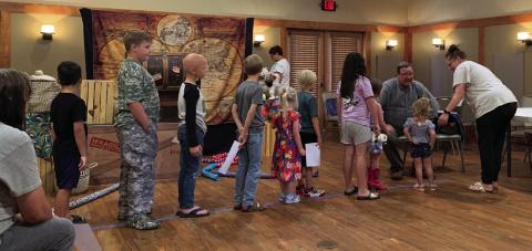 BALLOON FUN Summer reading program participants line up beside Wisconsin Johnson (Rick De Lung) for special request twisted balloon animals after the magic show put on by De Lung and his wife Kelley of Lubbock. | ANNA GIBSON