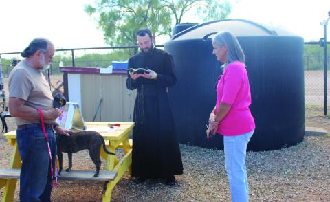 Father Jacob Powell of Holy Cross Catholic Church offered the Blessing of the Animals at the Post Animal Refuge Center last Tuesday during the feast of St. Francis of Assisi. Rick Jones, a volunteer at PARC, is shown with his dog as Father Powell gave the blessing, and Janice Plummer, also a PARC volunteer watches. Photo Provided