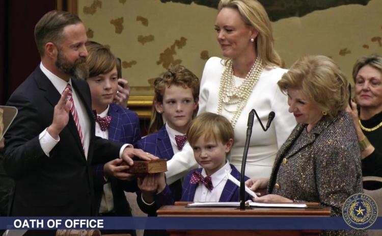 ELECTED TX SPEAKER State Rep. Dustin Burrows was administered the oath of office as Speaker of the Texas House by Secretary of State Jane Nelson (right) during opening day ceremonies on the House floor on Tuesday, Jan. 14, 2025, as Burrows’ wife, Elisabeth (in white dress), and children look on. | BOB DAEMMRICH FOR THE TEXAS TRIBUNE