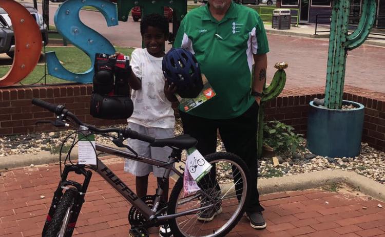 DRAWING WINNER Chris Atkinson presents X’yiah Martin, a drawing winner from July 4, with a 24” boys’ bike, along with knee and elbow pads, and helmet which was donated by the Post Community Recovery Center. | DAWN GRAVES PHOTO