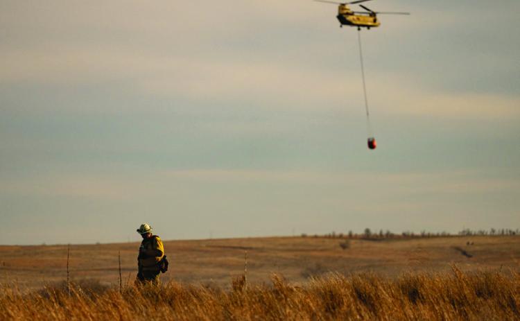 FIREAFTERMATH AfirefighterwalksaridgelineasaChinookhelicopter fliesoverranchlandcarryingwatertodumpontheSmokehouseCreek Fire in the Texas Panhandle after high winds reignited the record breaking fire. |TEXAS A&amp;M AGRILIFE SAM CRAFT PHOTO