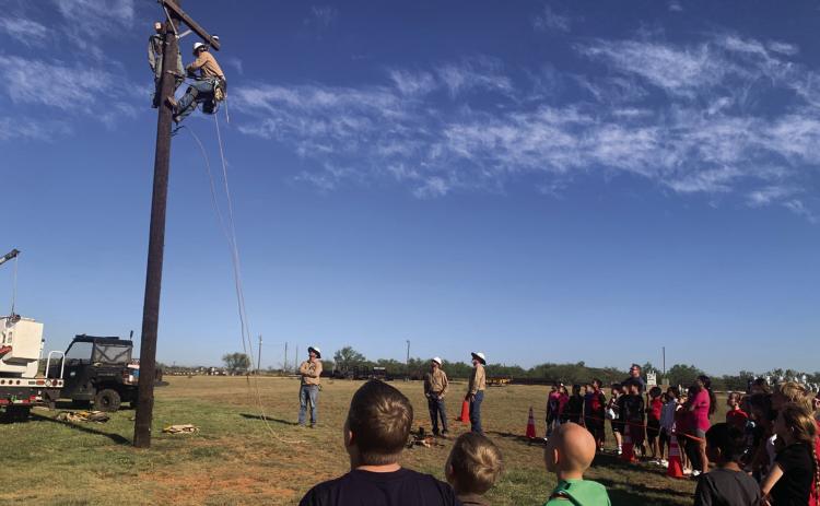 SURVIVAL PRACTICE Over 300 students from surrounding schools participated in South Plains Electric Company (SPEC) field trip. Students learned the importance of safety when working with electricity. New recruit Woodrow climbed the pole to save the dummy, Bob. The young onlookers watch with anticipation at what will happen next. | ANNA GIBSON PHOTO