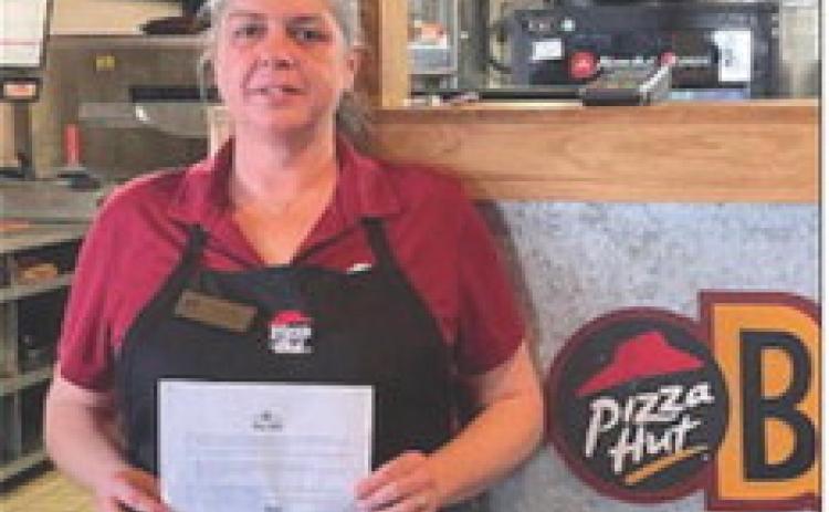 Liz Ruth holds the message from the Sr. Manager, Operations with a congratulations for being in the top 100 Pizza Huts in the nation.