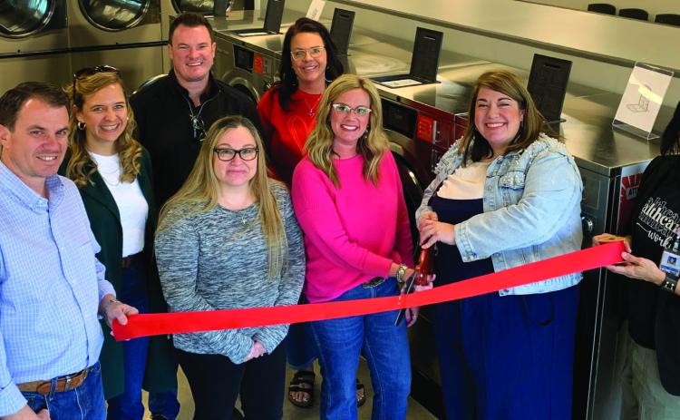 NEW LAUNDROMAT Amy Rektenwald and Hayley Mason cut the red ribbon during their grand opening on Jan. 16. Beside them on the left are Owners Jordan and Leigh Madewell, Tye Mason, Misti Day, Lupe Lazcano, and Christina Jones. | ANNA GIBSON PHOTO