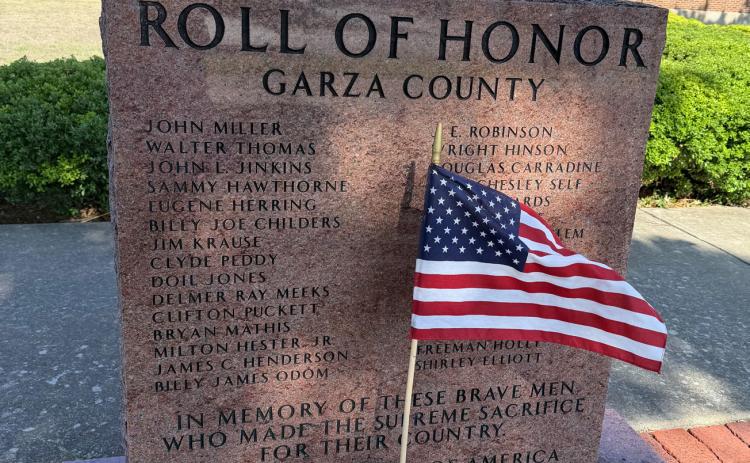 LASTING LEGACY A small American flag stands before the Garza County Roll of Honor monument on the courthouse square in Post, serving as a tribute to local servicemen who made the ultimate sacrifice in defense of the United States. | STEPHANIE ALLEN
