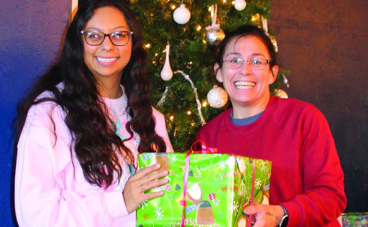 Dora Bishop, Headstart Family Services Coordinator, accepts the Winehouse 127 Angel Tree gifts from Michele Liston. Over 150 gifts will make their way to 41 children this Christmas season. Photo by Julia Childs