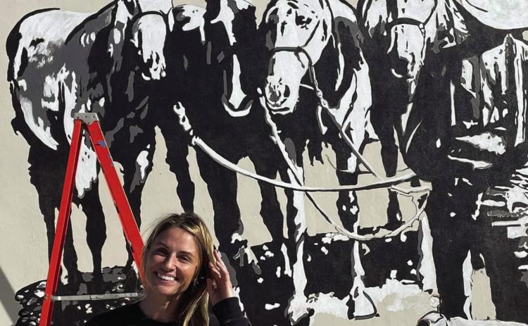 MOREMURALS Street Artist Calina Mishay Johnson stands in front of a mural she painted at City Hall. | PHOTO PROVIDED