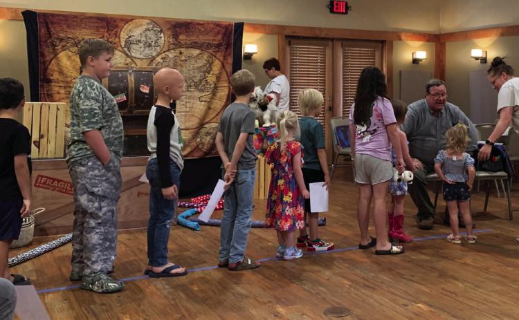 BALLOON FUN Summer reading program participants line up beside Wisconsin Johnson (Rick De Lung) for special request twisted balloon animals after the magic show put on by De Lung and his wife Kelley of Lubbock. | ANNA GIBSON